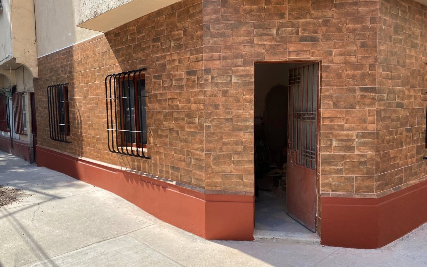 Fachada de un inmueble remodelada por Inspiratta en Ciudad de México, con recubrimiento tipo ladrillo y zócalo terminado.